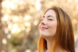 Portrait of a beautiful woman doing breath exercises with an autumn unfocused background